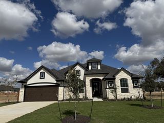 A beautiful stone-accented home with a lush yard in Broken Oak by Chesmar Homes (Georgetown, TX).