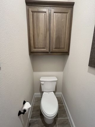 A cozy bathroom with elegant wooden cabinets, neutral walls, and tiled flooring for a modern touch.