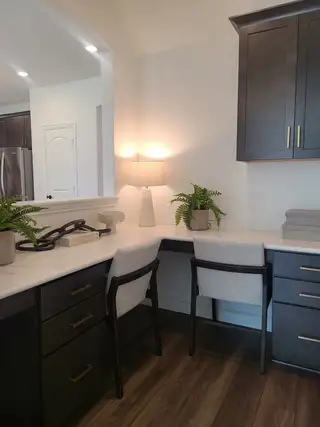A modern workspace featuring dark cabinetry, elegant lighting, and vibrant greenery for a refreshing home office vibe.