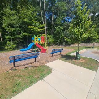 Colorful playground with blue benches and lush trees in Paces Estates by McKinley Homes (Lithia Springs, GA).