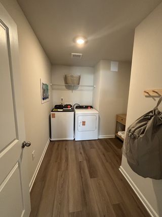 A cozy laundry room featuring a washer, dryer, and wooden flooring.