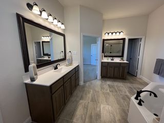 A luxurious bathroom featuring dual vanities, elegant lighting, and a spacious layout with contemporary finishes.