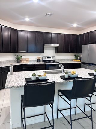 A modern kitchen with sleek dark cabinets, a granite island, and stylish bar stools, perfect for entertaining.