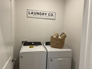 Model Home A cozy laundry room with a modern washer, dryer, and decorative basket under a stylish "Laundry Co." sign.