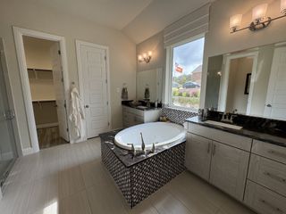 A luxurious bathroom featuring a marble-topped tub, elegant vanity, and chic lighting, creating a serene oasis.