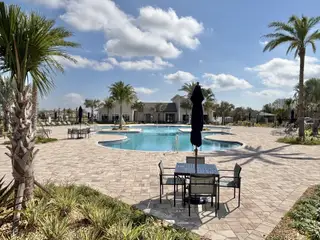 A luxurious pool area with palm trees and seating in Storey Creek: Estate Collection by Lennar (Kissimmee, FL).