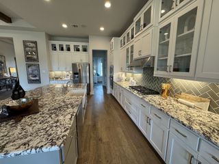 Model Home A luxurious kitchen with white cabinetry, granite countertops, and a large island.