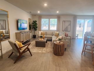 Model Home A cozy living room with a sectional sofa, stylish armchair, and wall-mounted TV, featuring soft lighting and modern decor.