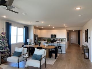 A spacious open-concept living area with a modern kitchen, cozy seating, and festive decor, featuring elegant lighting and wood flooring.