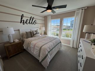 Model Home A cozy bedroom with striped bedding, large windows, and decorative wall art in a soothing, neutral palette.