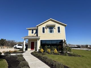Street view Charming yellow house with red door and landscaped yard in Edgebrooke by Brohn Homes, Pflugerville, TX.