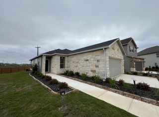 A charming stone home with a well-maintained lawn and modern design in Davis Ranch by Pulte Homes (San Antonio, TX).