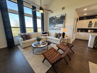 A cozy living room with large windows, elegant curtains, a chic sectional, and wooden flooring, combining comfort and style.
