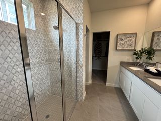 A modern bathroom with a glass shower, patterned tiles, sleek vanity, and elegant decor.