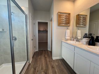 A modern bathroom featuring a glass shower, dual sinks, and elegant artwork on the walls.