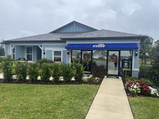 Street view A charming home with a blue awning and landscaped yard in Marion Ranch by Pulte Homes, Ocala, FL.