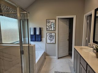 A modern bathroom featuring elegant marble flooring, a chic glass shower, and tasteful floral artwork.