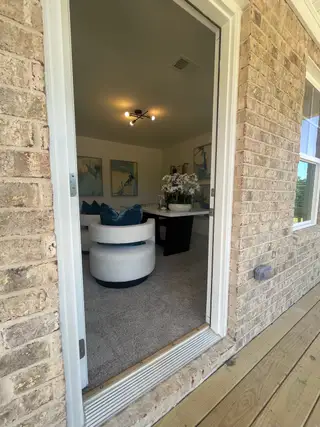 A cozy living area with plush carpet, modern seating, and stylish decor viewed through a doorway.