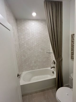 A modern bathroom featuring hexagonal tiles, a sleek tub, and elegant curtains with soft lighting.