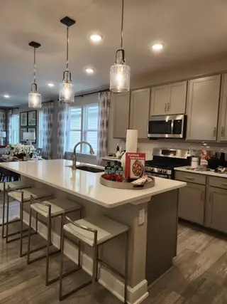 A modern kitchen with sleek cabinetry, a spacious island, pendant lighting, and stainless steel appliances.