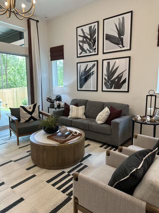 A modern living room with a gray sofa, abstract artwork, and wooden accents, filled with natural light.