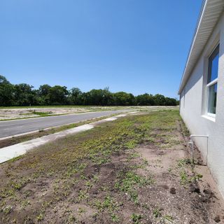 Expansive plot and roadside view in Yucatan Gardens by CFB Homes, Azalea Park, FL, under clear blue skies.