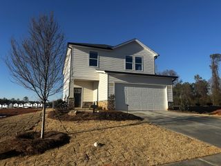 A white two-story home with a spacious garage, landscaped surroundings, and a long driveway.