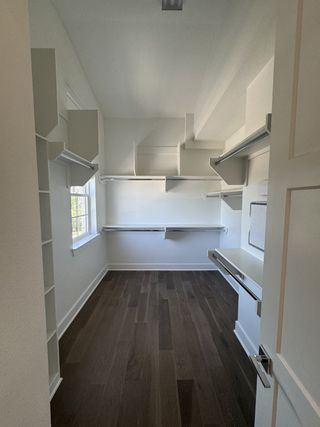 Model Home A spacious walk-in closet with sleek shelving, hardwood floors, and abundant natural light.