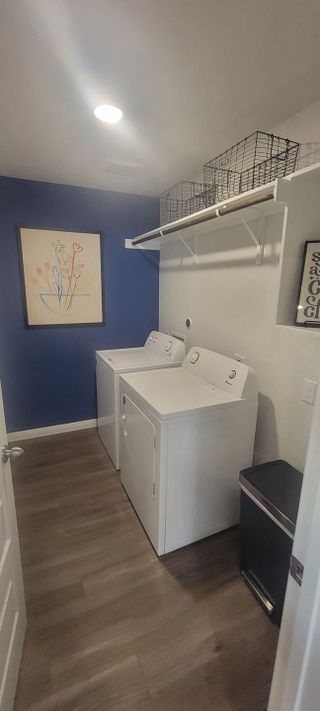 A sleek laundry room with white machines, blue accent wall, and modern artwork.