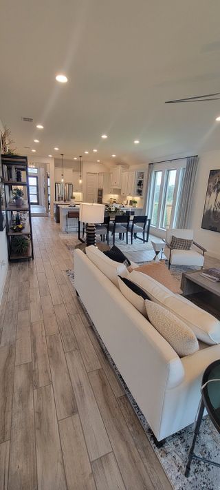 An open-concept living space with warm wood flooring, modern furniture, and abundant natural light, seamlessly blending comfort and style.