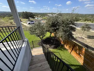 Street view A view from an elevated deck with wooden stairs, overlooking a landscaped yard and community amenities in Sweetwater by Pulte Homes (San Antonio, TX)
