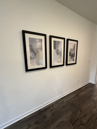 A modern hallway featuring dark wood floors and minimalist framed art.