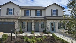 A charming brick duplex with shutters and manicured landscaping in Palomino by D.R. Horton (Manor, TX).