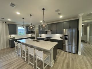 A chic kitchen with sleek gray cabinets, modern pendant lights, and a spacious island with seating.