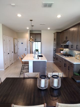 A contemporary kitchen with sleek cabinets, an island, pendant lighting, and dining area featuring woven decor accents.