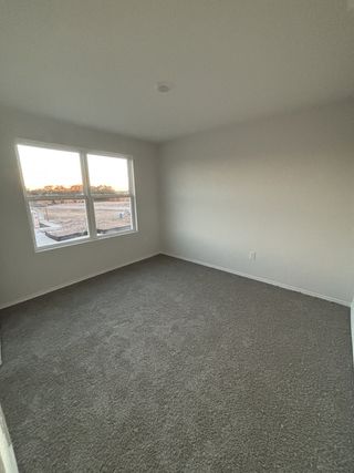 A cozy room featuring soft carpet flooring, neutral walls, and a large window for ample natural light.