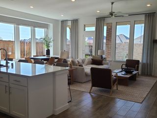 Model Home A bright living area with large windows, modern furniture, and a kitchen island, creating an inviting open-concept space.