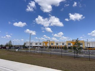 A modern building with vibrant yellow accents and ample parking in Scenic Terrace by Taylor Morrison (Lake Hamilton, FL).