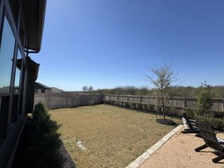 A spacious backyard with lush grass and a gravel seating area, perfect for relaxation and outdoor activities.