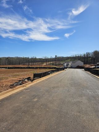 Street view A spacious street view in Ponderosa Farms by Chafin Communities in Gainesville, GA, featuring a freshly paved road, new construction, and a bright blue sky.
