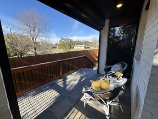 A cozy covered patio with stylish seating and a wooden railing.