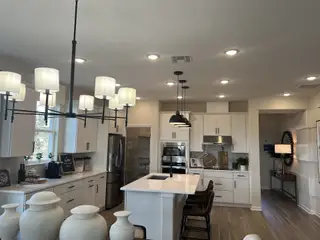 A spacious kitchen featuring sleek white cabinets, modern lighting, and a central island with seating.