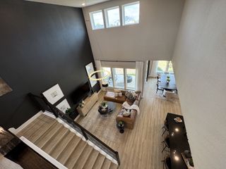 Elegant open-concept living room with plush seating, airy dining space, and sleek kitchen counter, featuring high ceilings.