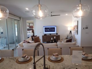 Model Home A cozy living room with chic lighting, a plush sofa, and a modern kitchen view.