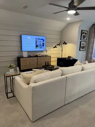 Model Home A cozy living room featuring a plush sectional, sleek TV setup, and modern accents with stylish lighting.