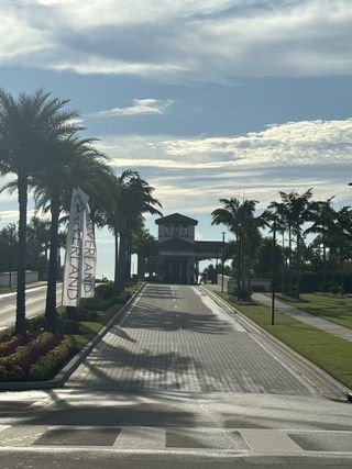 Street view A grand entrance with palm-lined drive and lush landscaping at Valencia Walk at Riverland by GL Homes (Port St. Lucie, FL).