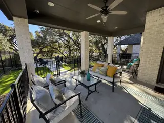 A cozy covered patio with stylish outdoor seating, perfect for relaxation and entertaining with scenic backyard views.