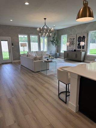 A spacious living area with elegant lighting, cozy seating, modern decor, and large windows overlooking a fenced backyard.