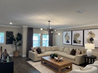 A cozy living room featuring a neutral sectional, abstract artwork, modern chandelier, and wooden coffee table.