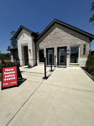 A modern brick building with sleek design in Hills of Westlake by D.R. Horton (Conroe, TX), featuring a new home sales event sign.